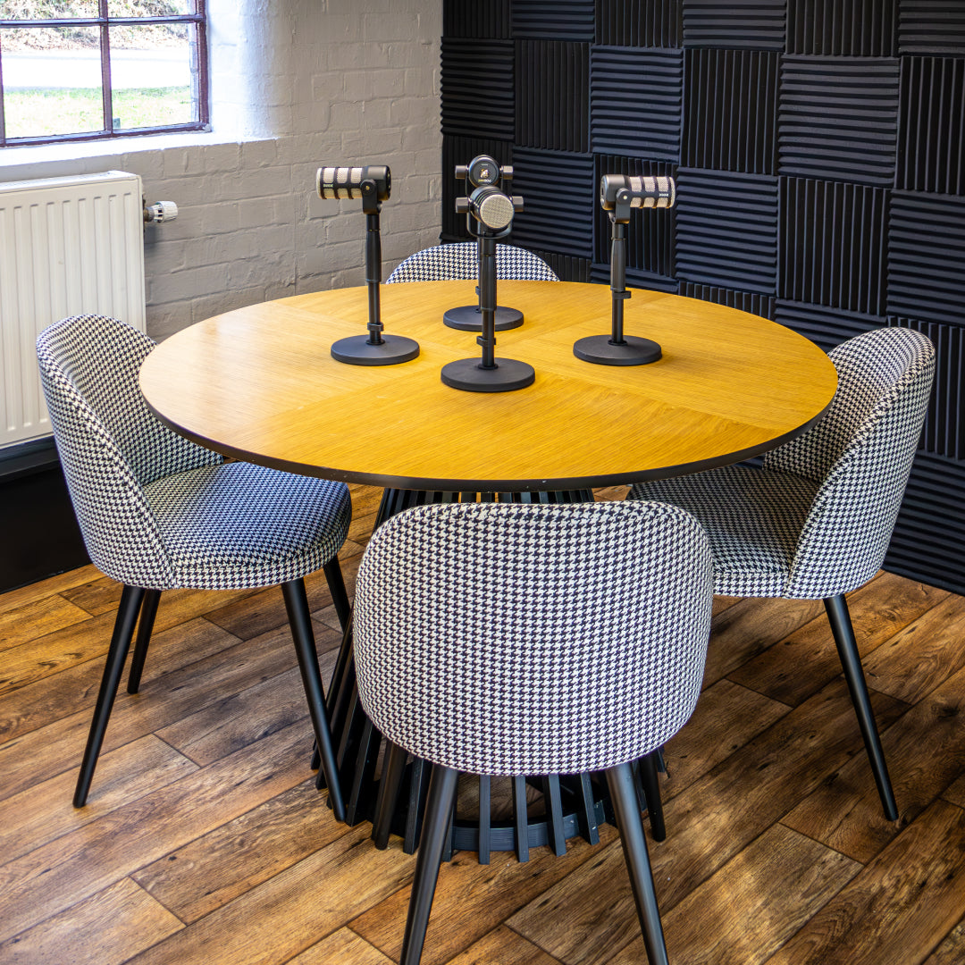 Dash Spaces' four-seat podcast table with four microphones and acoustic wall panels.